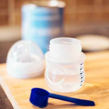 bottle and formula scoop used during newborn feeding schedule