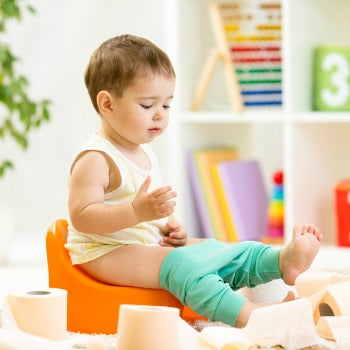 side view of toddler sitting on potty chair with legs outstretched