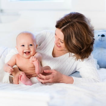 mother and baby laughing together on a bed