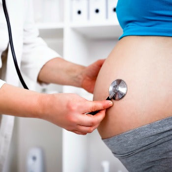 Doctor listening to pregnant woman's stomach in her third trimester