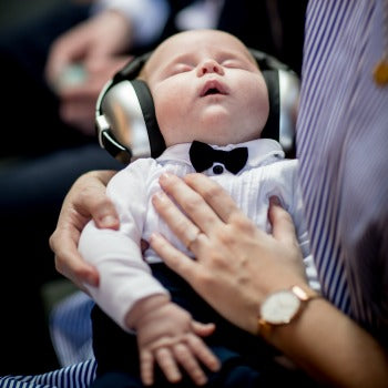 parent soothing and protecting baby's ears with a headset while traveling with baby