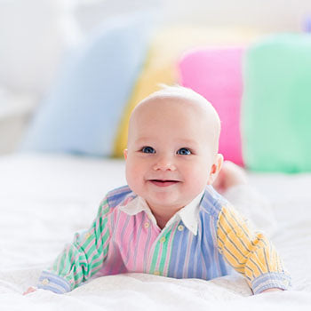 happy baby lying on tummy on a bed