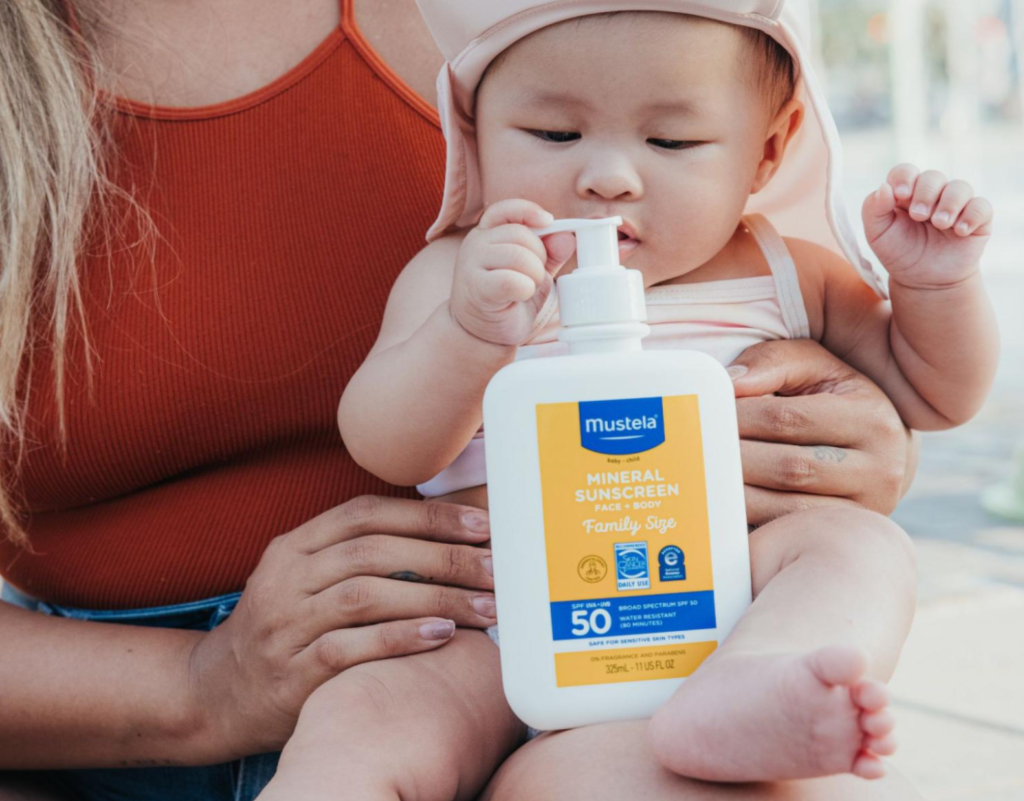 Baby playing with a sunscreen bottle