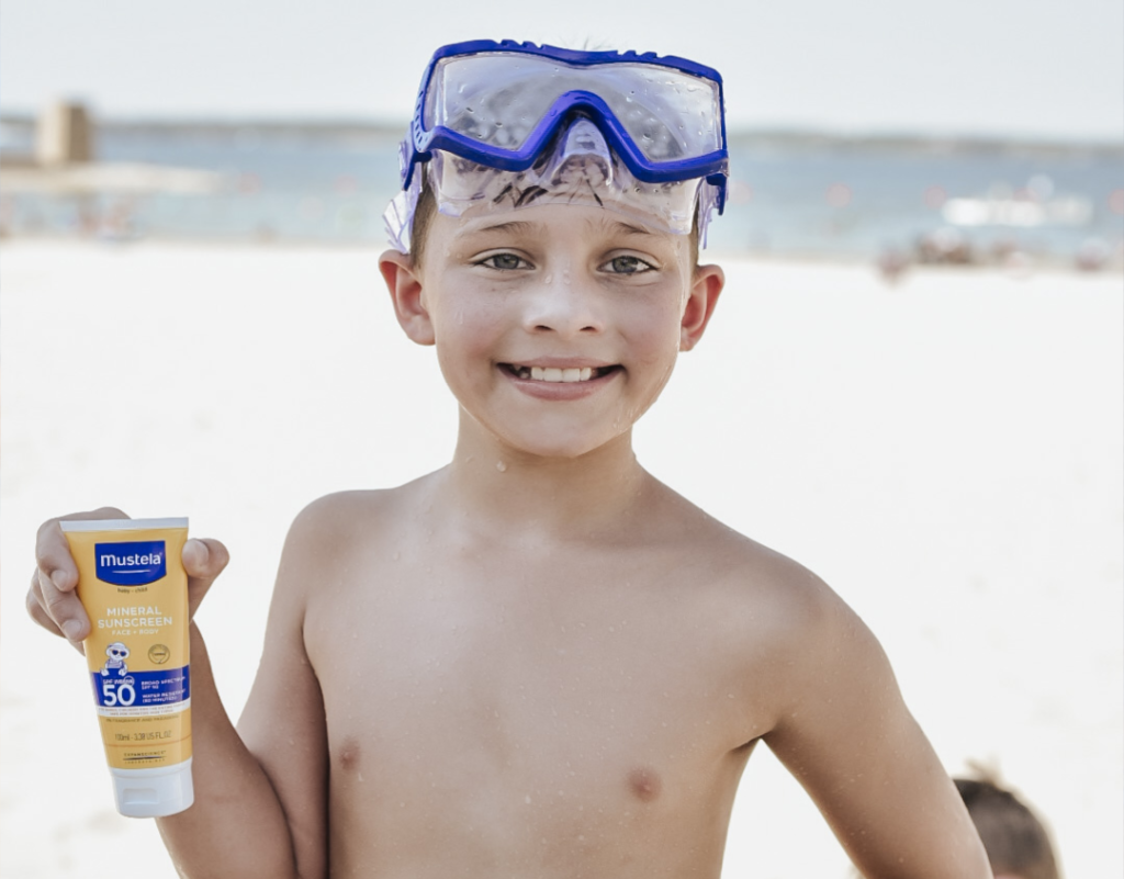 Kid holding sunscreen at the beach