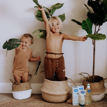 Kids playing next to Mustela skin products with emollients