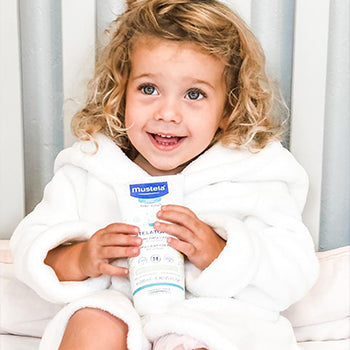 Young girl holding Mustela skin products after taking a bath