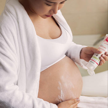 Mustela stretch marks cream being applied to a woman's pregnant belly