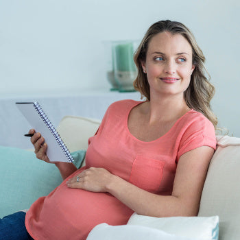 Pregnant woman writing in pregnancy journal