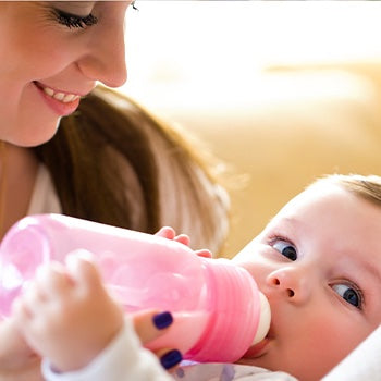 Mom holding bottle while baby is eating