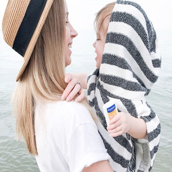 Mom holding son whose protected by hypoallergenic sunscreen