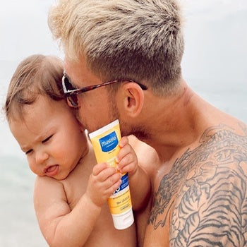 Dad keeping baby safe in the sun with hypoallergenic sunscreen