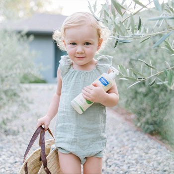 baby outside holding a bottle of Micellar water