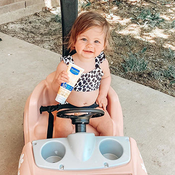 baby holding Mustela mineral sunscreen