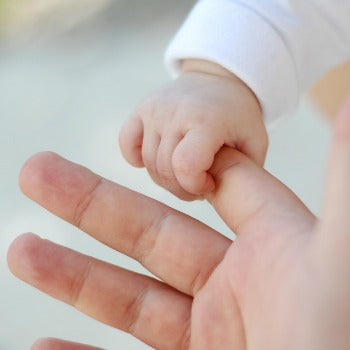 baby holding onto parents finger