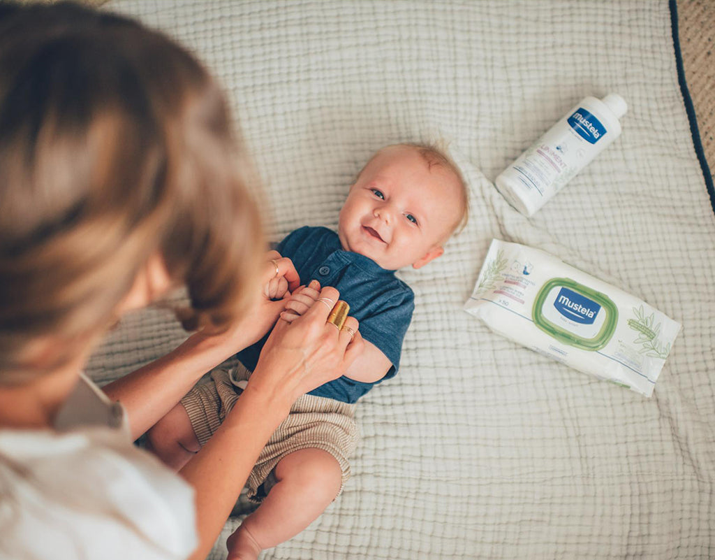 Mom changing baby diapers with newborn must-haves from mustela