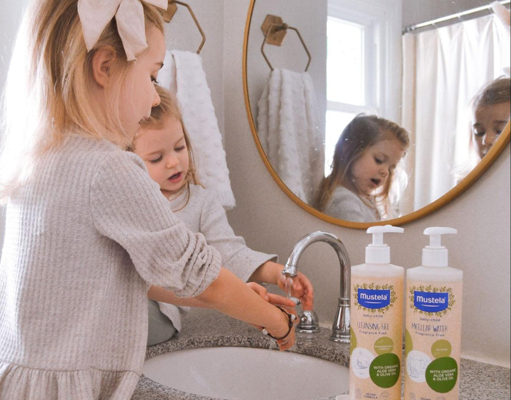 Two siblings washing their hands with mustela products