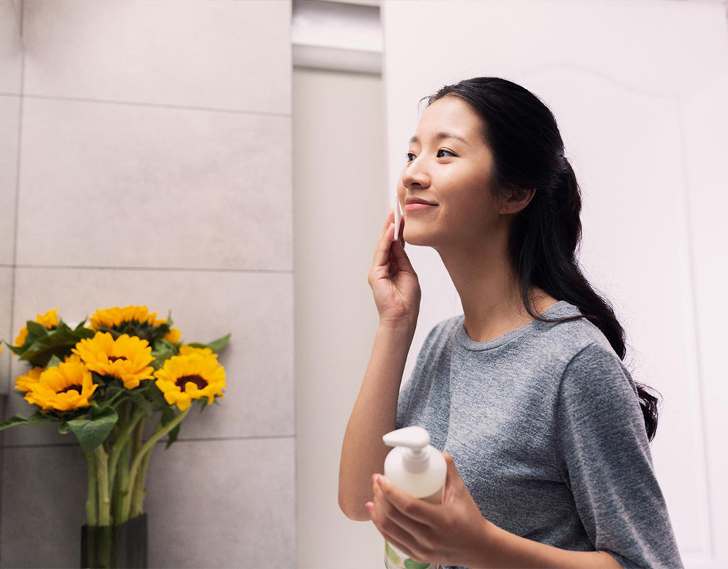 Woman applying olive oil for skin with a cotton pad