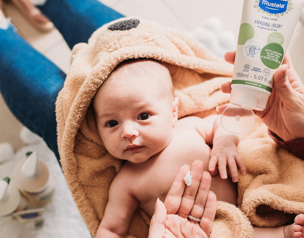 Mom applying organic baby cream on newborn