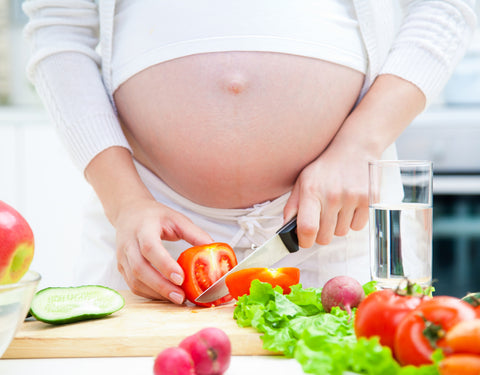 Pregnant woman cutting vegetables