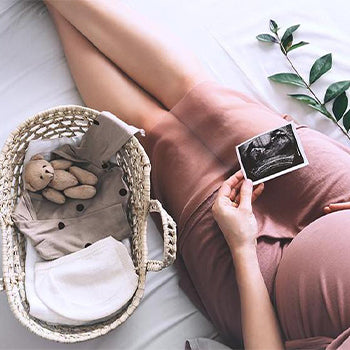 Woman with pregnant belly holding a sonogram photo