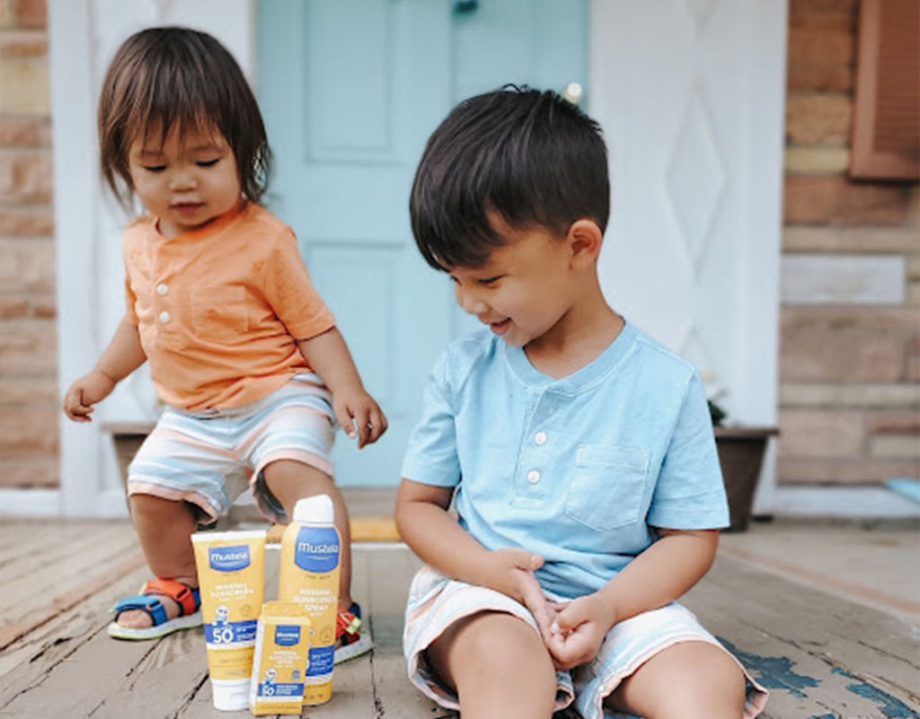 Two kids with Mustela Sun products that help prevent a red cheeks toddler