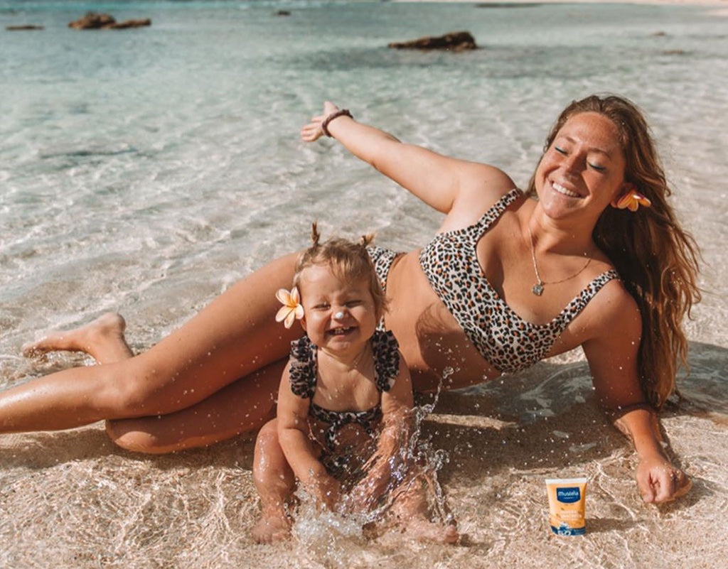 Mom and daughter at the beach laying in the water