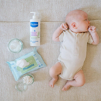 baby laying next to Mustela products