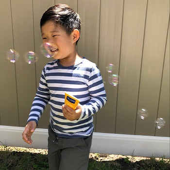 Kid playing with bubbles while using mustela sunscreen