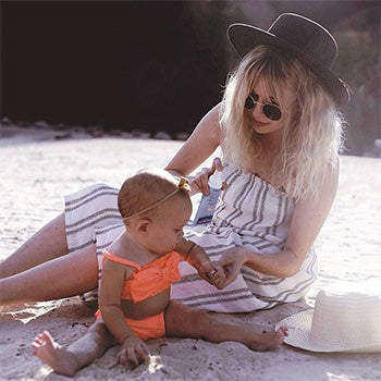 Mom applying spray sunscreen on child