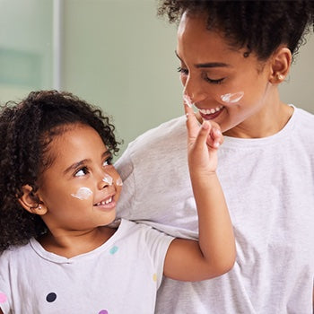 Child applying sunscreen for eczema to moms face