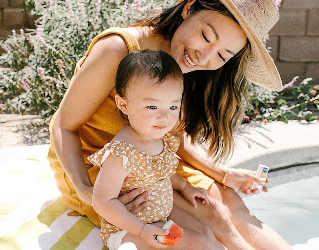 Mom protecting kid at the pool with sunscreen for sensitive skin