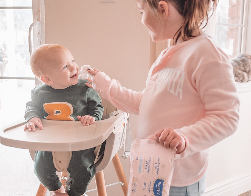 Sister cleaning siblings face with sustainable baby products