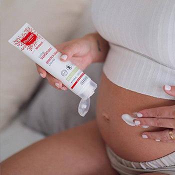 Woman applying cream on belly during third trimester