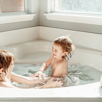 two kids taking a bath to help with eczema