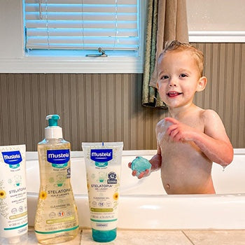 Baby taking a bath with Mustela skin products to help with eczema