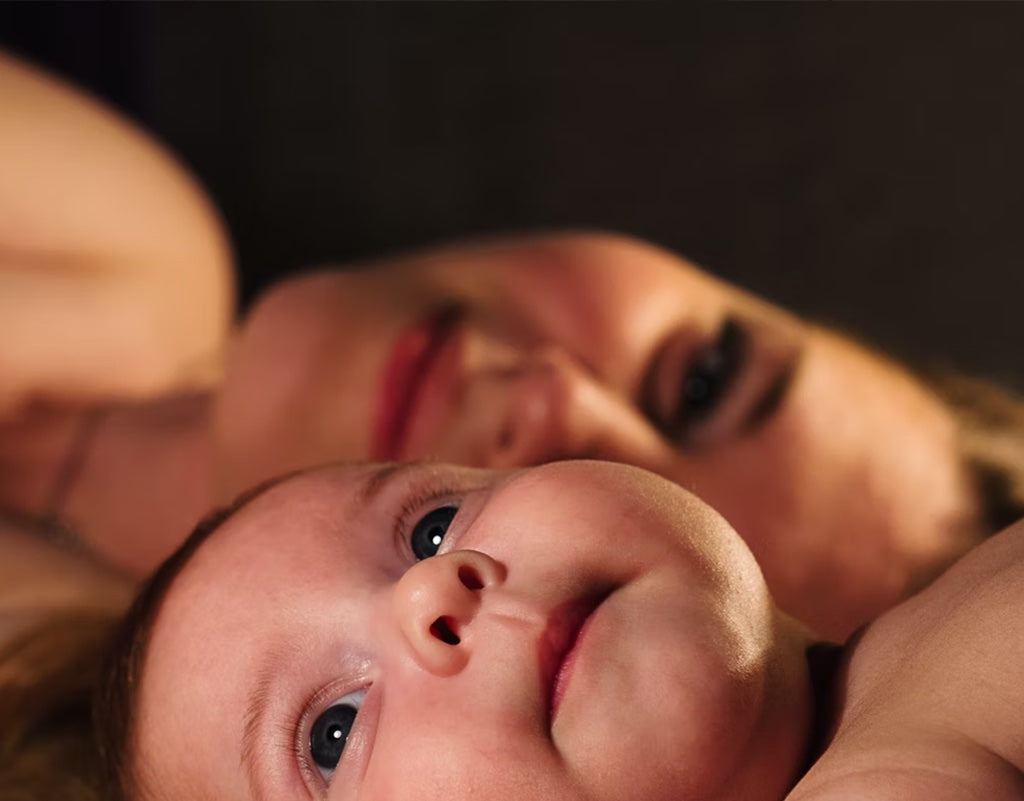 Mom laying with baby with light from the window shining through