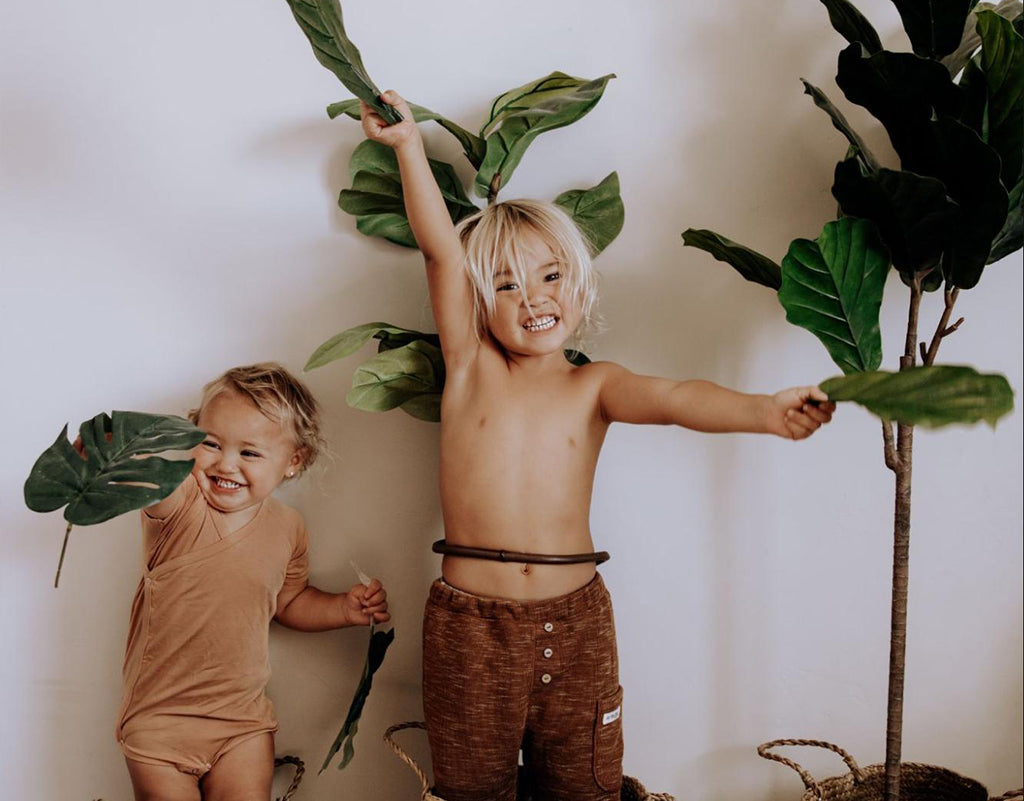 Two kids playing around with fake plants