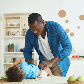 Baby being changed and Dad is wondering when do babies start rolling over