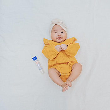 Cute baby on back wearing a yellow onesie