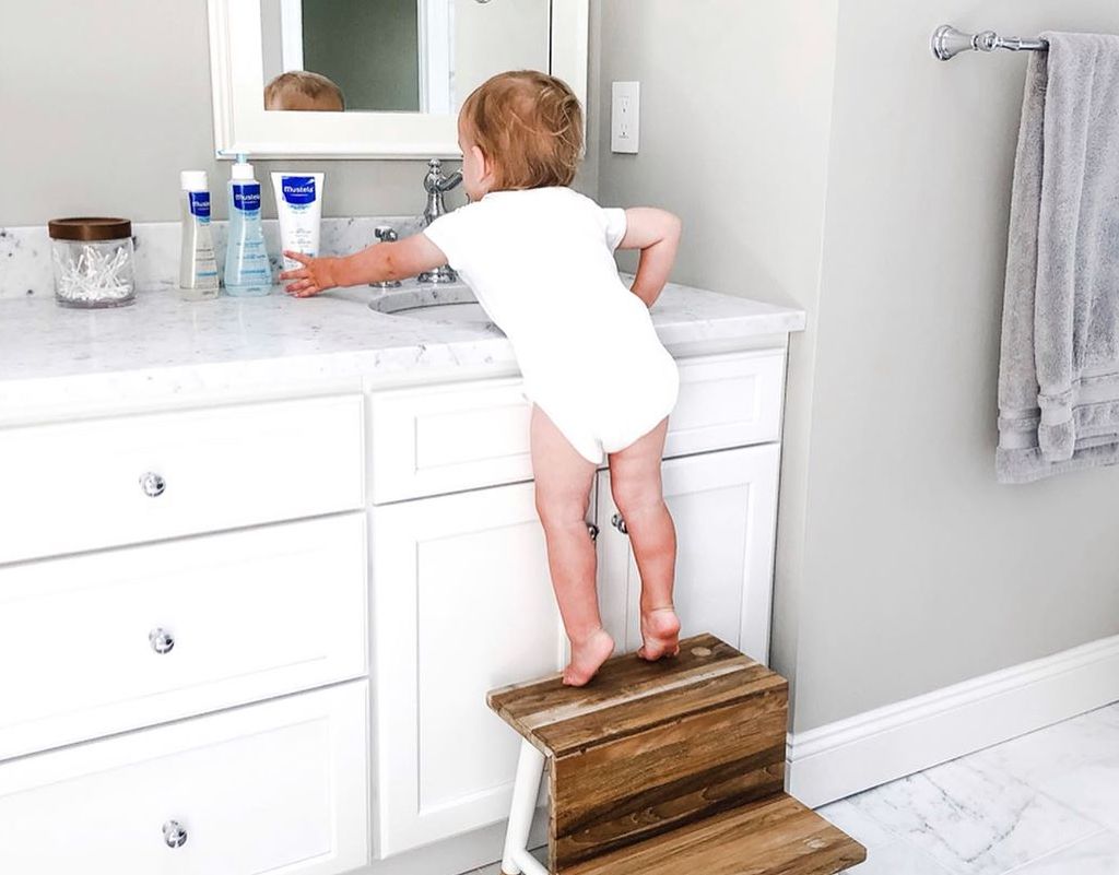 Child on step stool trying to wash hands