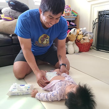 father changing babies diaper