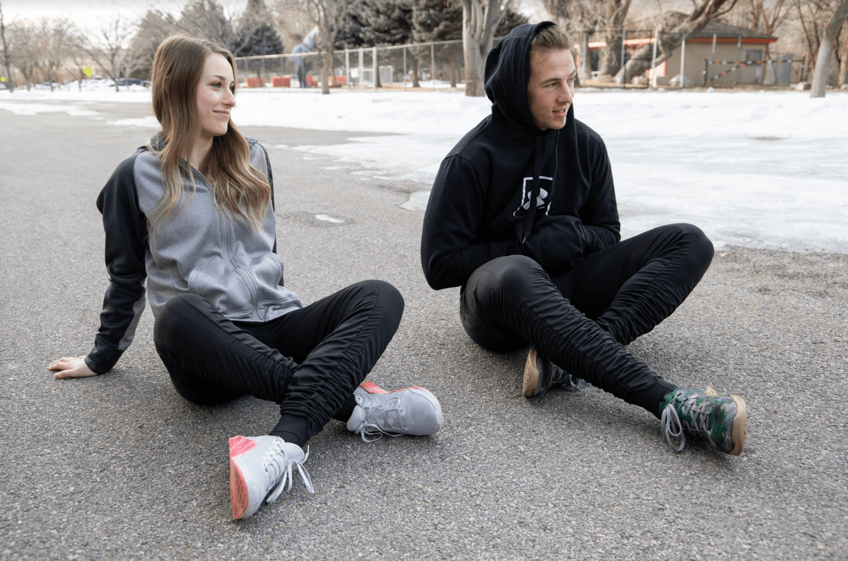 couple sitting outside on the pavement in the winter wearing Agogie resistance pants