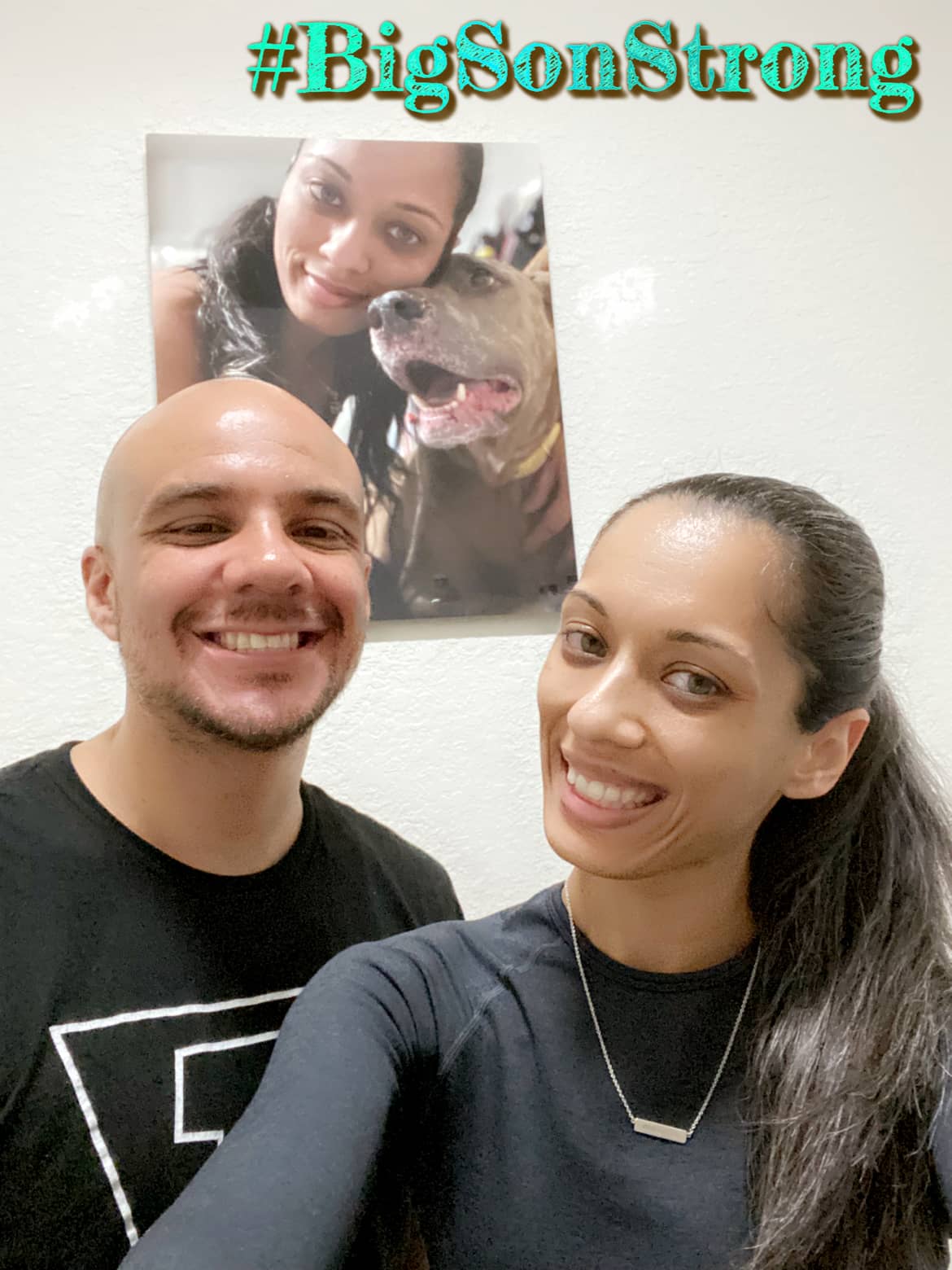 Kumarie and her husband in front of a picture of their darling pup