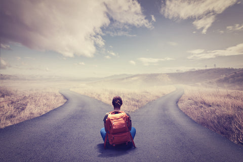 Woman with backpack sitting at crossroads