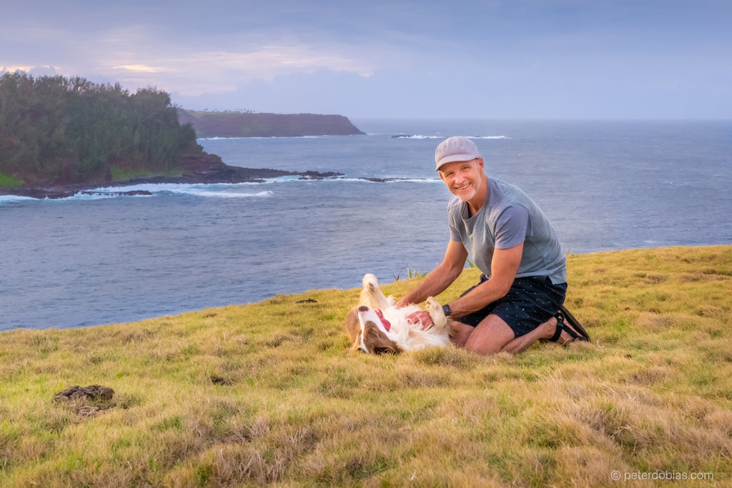 Dr. Dobias and his dog Pax sitting on grass overlooking the ocean