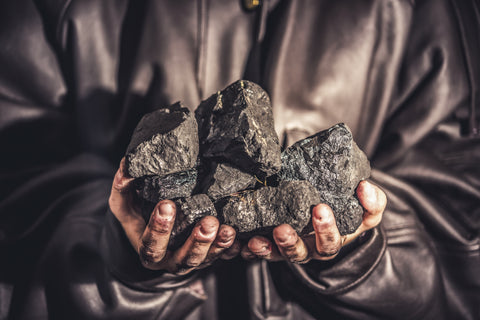 Hands holding chunks of black coal