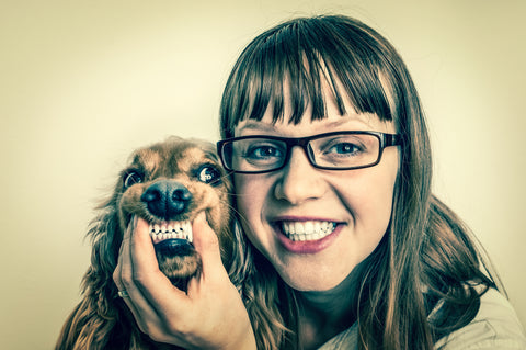 Woman with smiling dog, showing healthy teeth