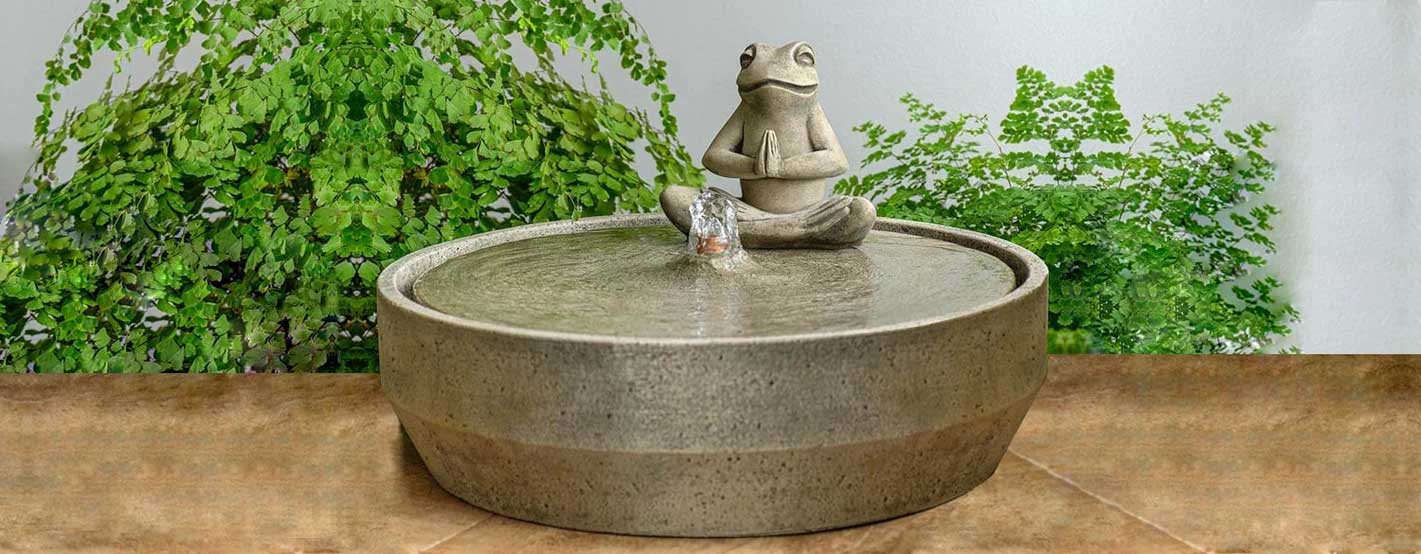 Beveled Yoga Frog Fountain on table against green leaves