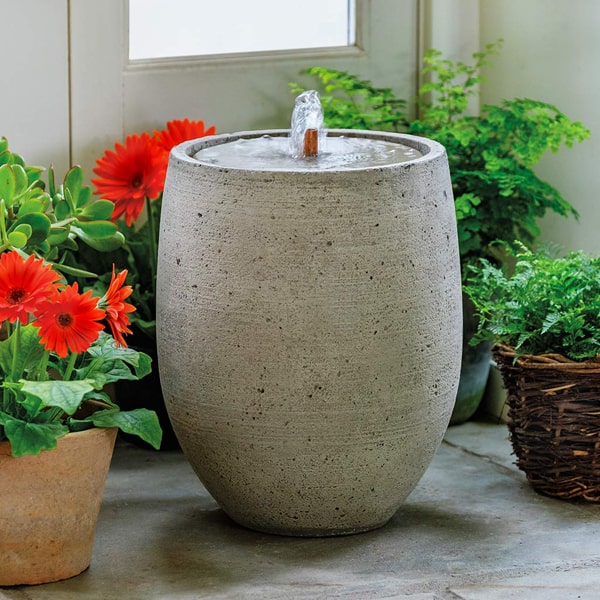 Campania International Bebel Fountain on concrete beside orange flowers