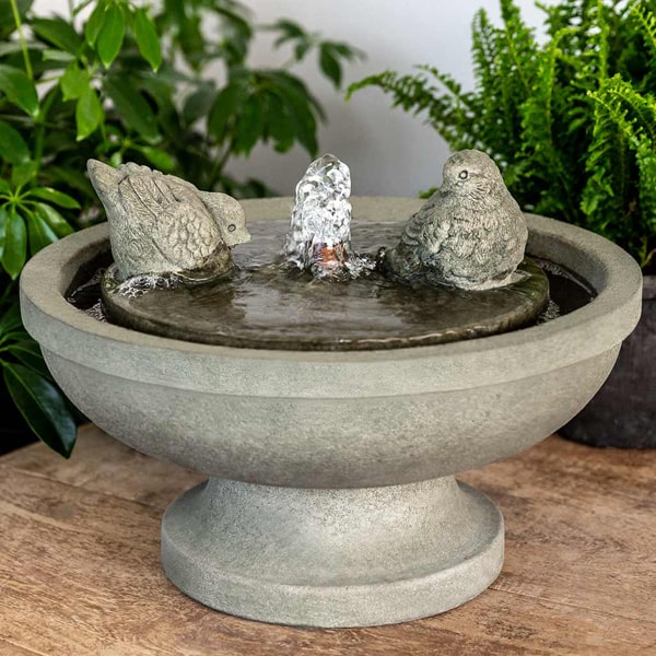 Campania International Belleville Fountain running beside green plants